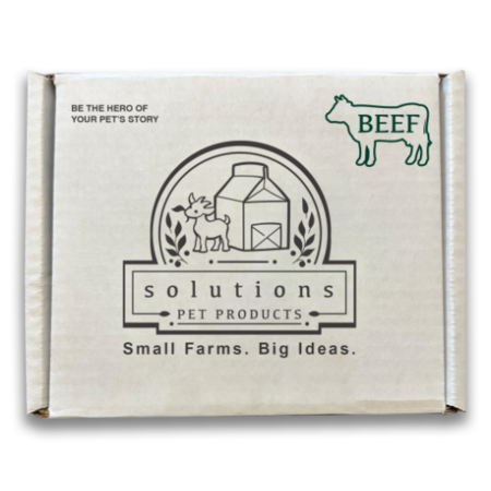 A square cardboard box for Solutions Pet Products, featuring a cream-colored front panel with black and green printed graphics and text, including a cow outline labeled BEEF.