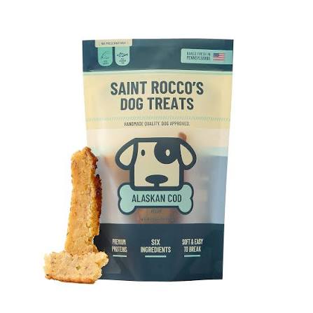 A stand-up pouch of Saint Rocco's Dog Treats Alaskan Cod recipe, shown with two dog treats leaning against the lower left side on a plain white background.